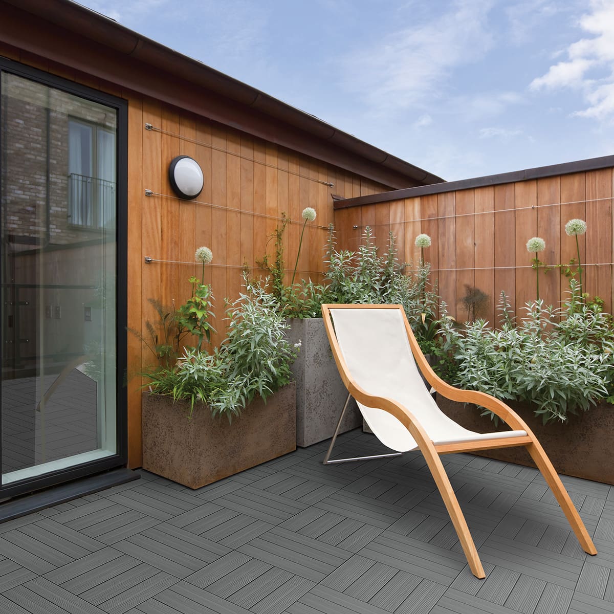 Terrasse moderne avec chaise longue et plantes.